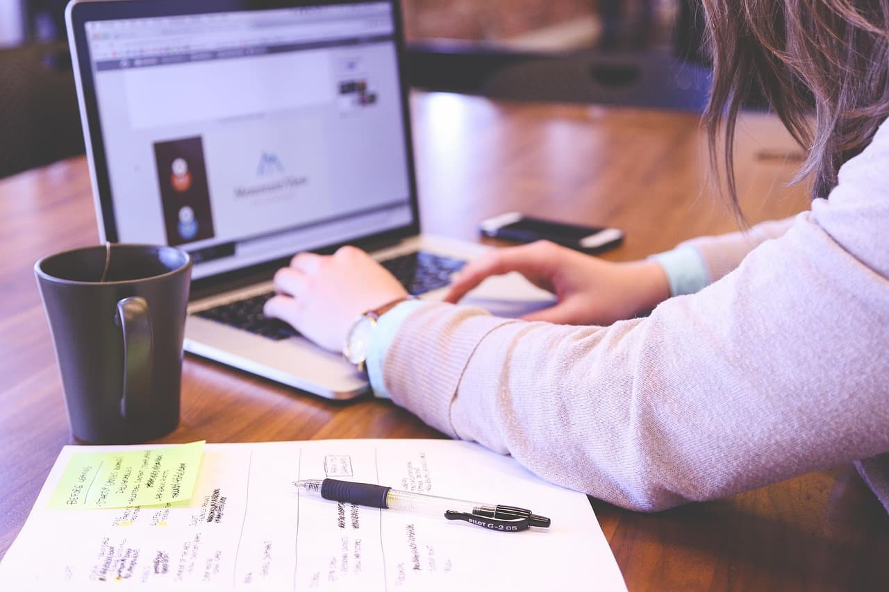 A person working on a laptop with coffee at a cafe table